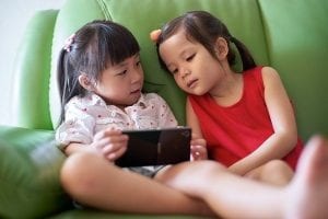 2 girls reading on a smart device